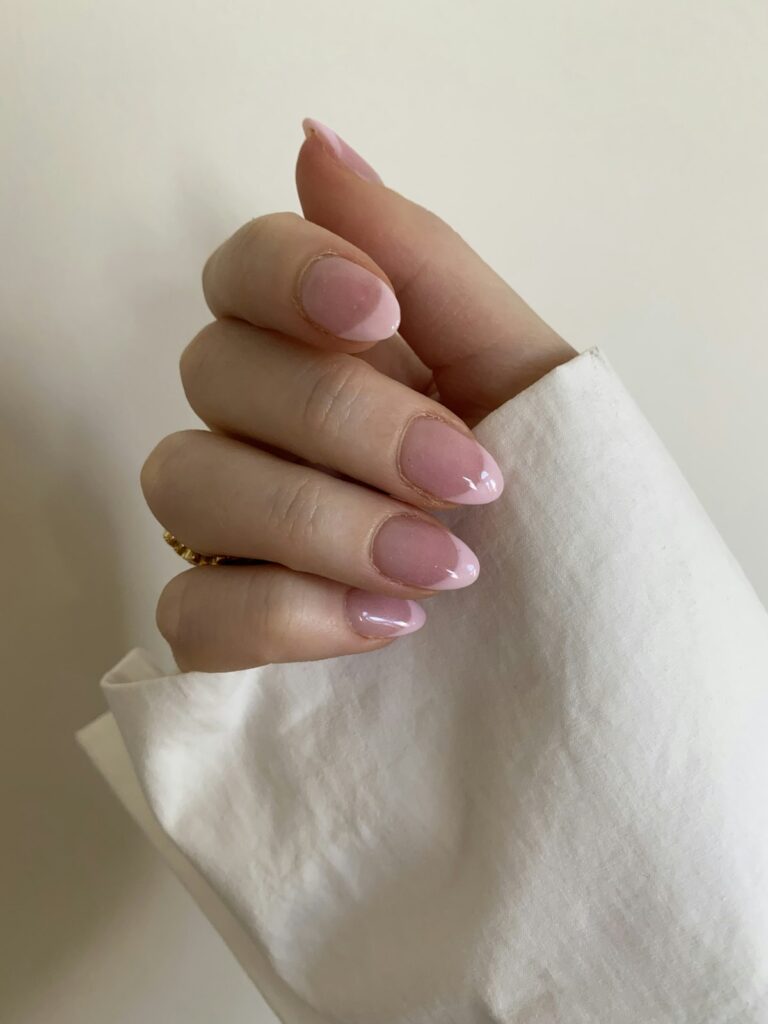 Leona Nails – Shellac Hand mit rosa Shellac-Nägeln auf weissem Stoff