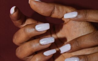 Galerie – Milky White Hände mit weissem Nagellack vor dunklem Hintergrund