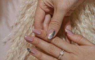 Galerie – Nude mit Ring Hände mit Nude-Maniküre und Ring auf hellem Fell
